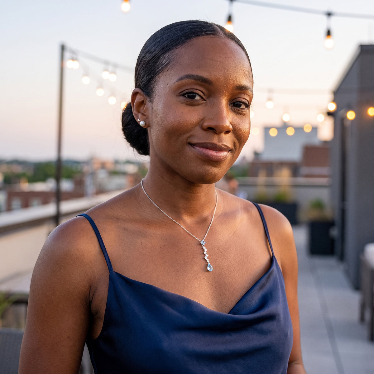Woman in a navy satin dress wearing the Ocean Tear necklace