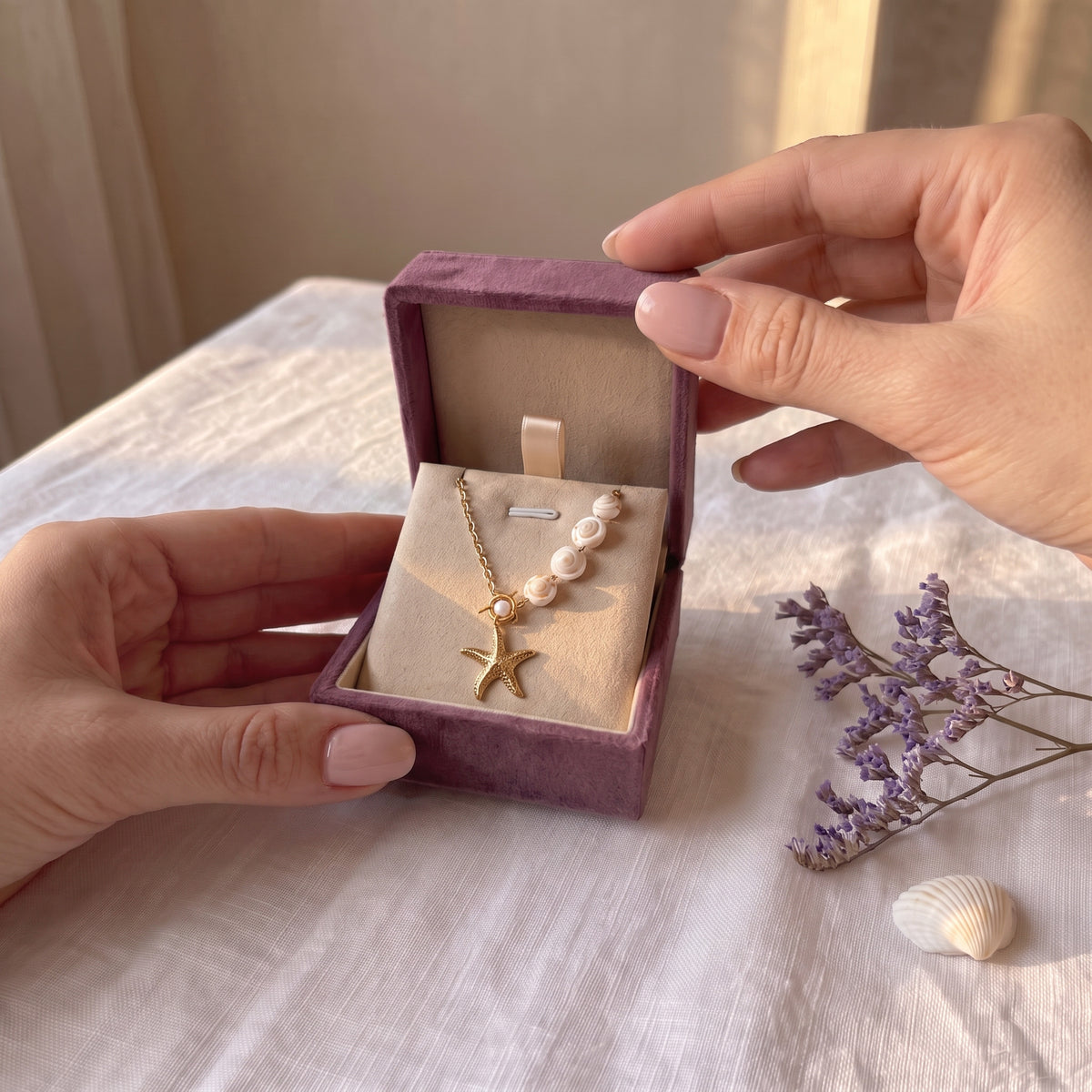 Hands opening the Storyelle gift box with the Golden Tide necklace