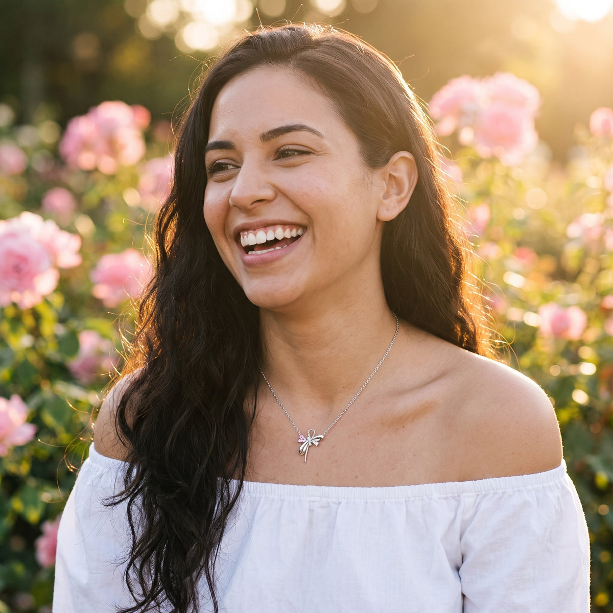Smiling woman wearing the Aurora Pink Bow necklace
