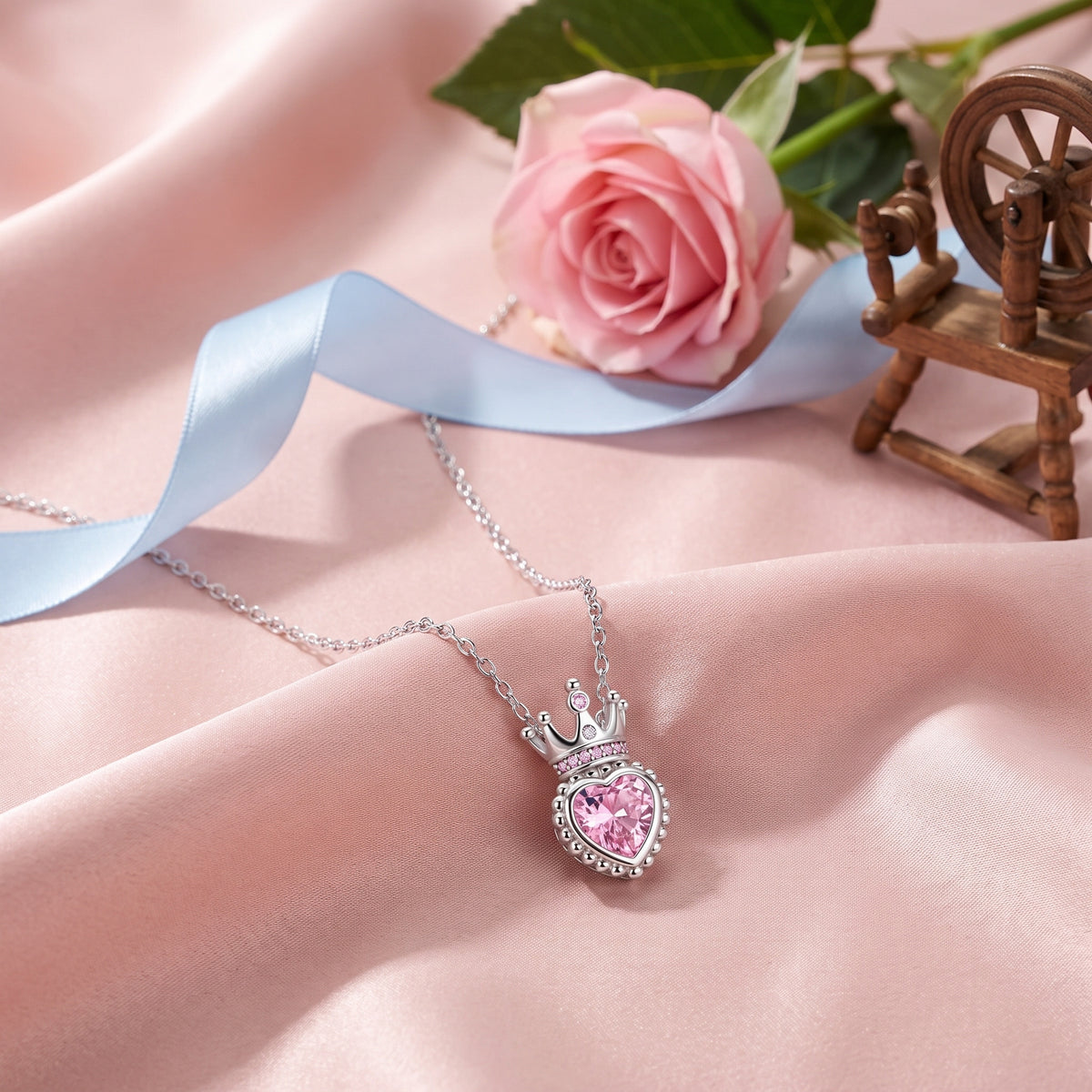 The Rose Crown necklace on pink satin with a rose and a spinning wheel