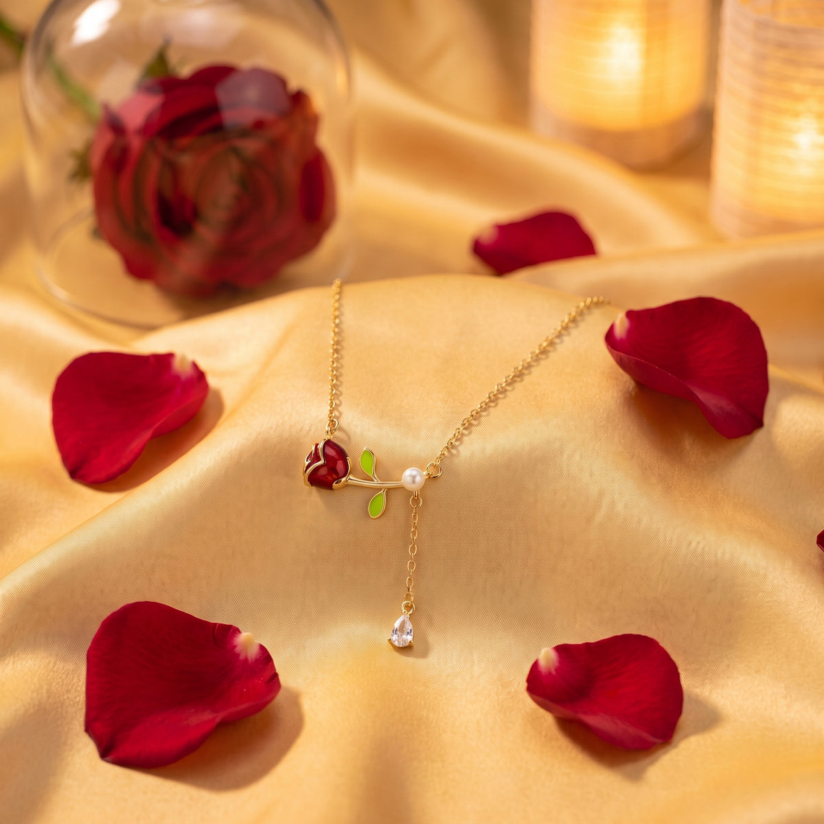 The “Belle” Pearl Rose Necklace resting on golden satin with red rose petals
