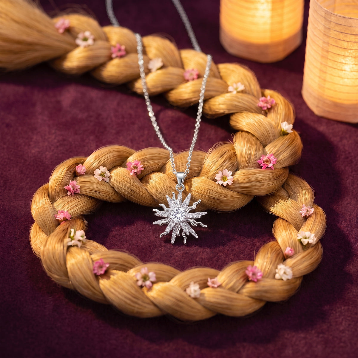 The “Rapunzel” Sun Drop Necklace in Spinning Silver resting on a golden flower braid