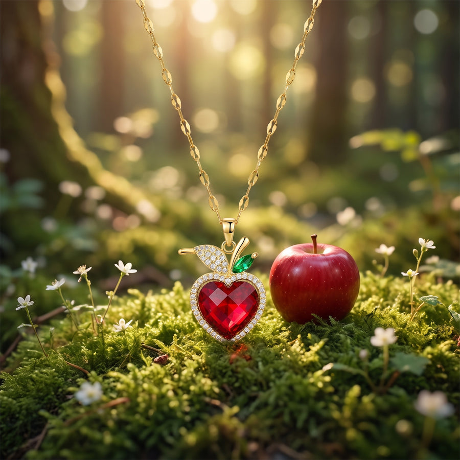 The “Snow White” Crimson Heart Necklace on forest moss beside a red apple