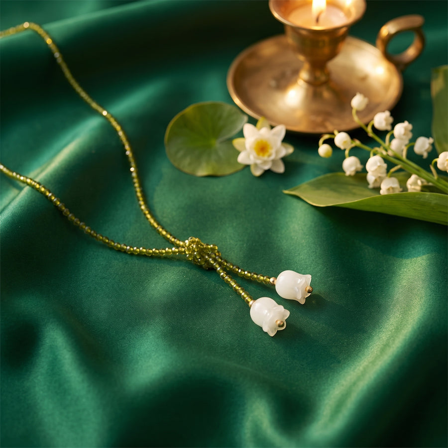 The “Tiana” Emerald Lily Necklace on emerald satin with lily of the valley, a water lily and golden candlelight