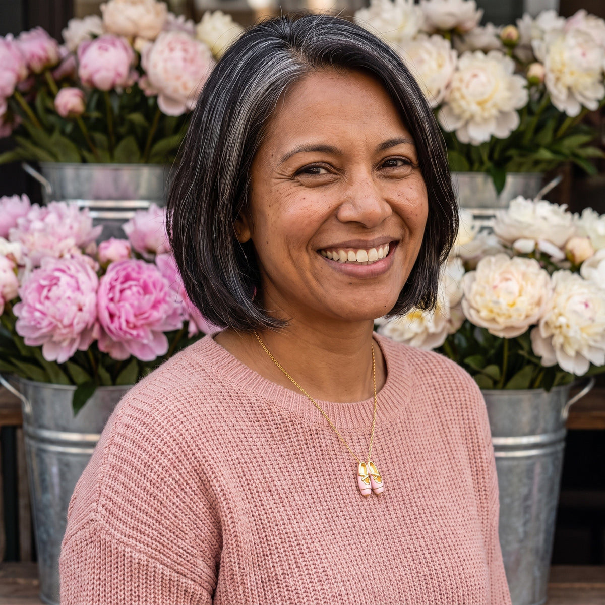 Smiling woman wearing the Pink Ballet Gold necklace