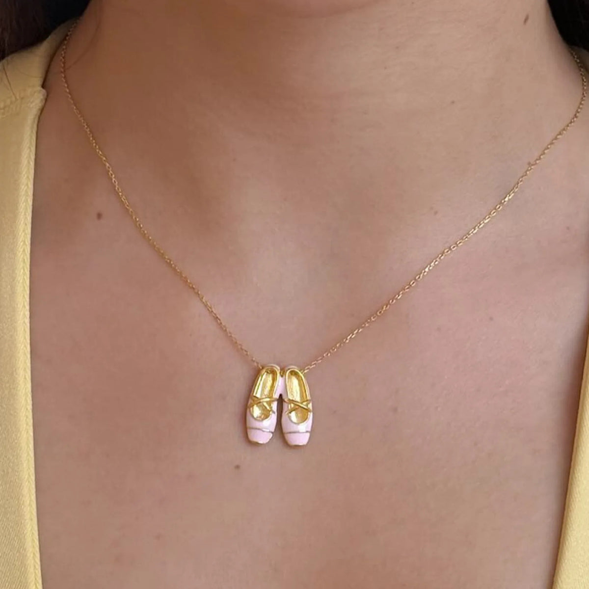 A ballet slipper necklace shown at its true size