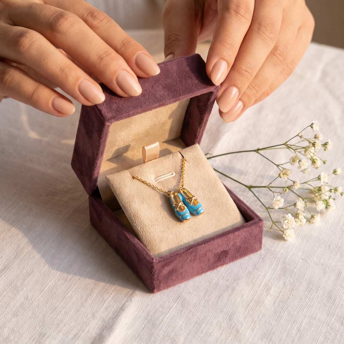 Hands opening the Storyelle gift box with the Blue Ballet Gold necklace