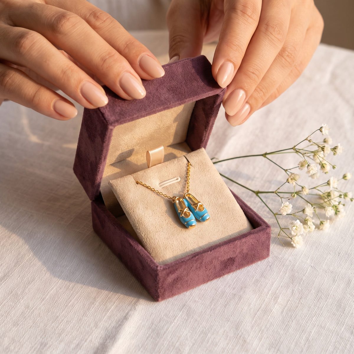 Hands opening the Storyelle gift box with the Blue Ballet Gold necklace