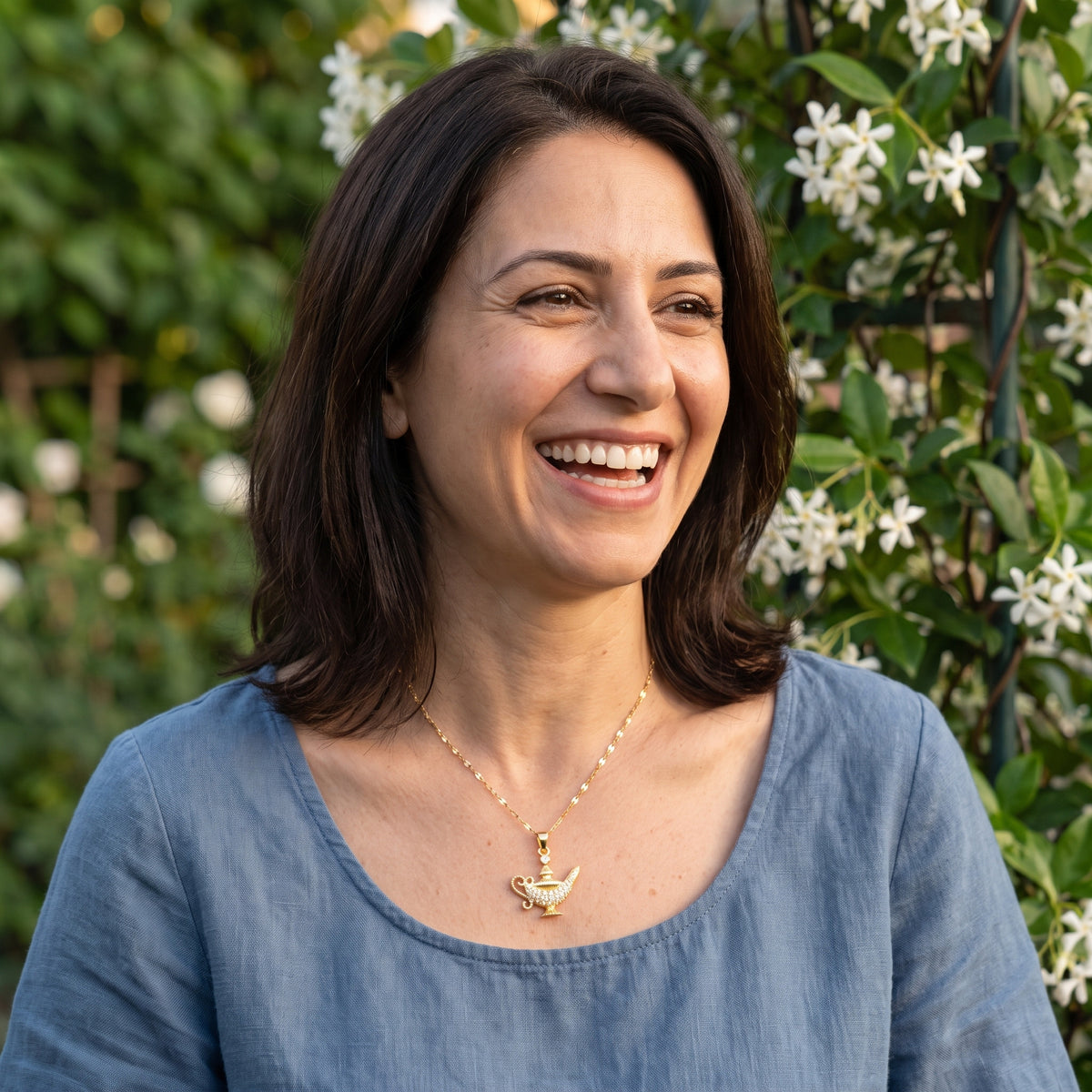 Smiling woman wearing the Jasmine Starlight Lamp necklace