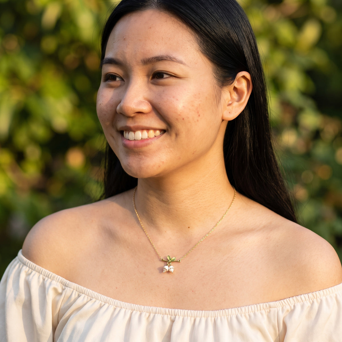 Smiling woman wearing the Tiana Golden Lily necklace
