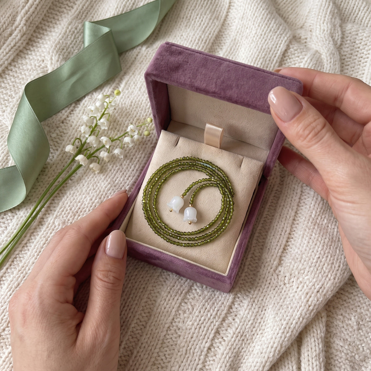 Hands opening the Storyelle gift box with the Emerald Lily necklace